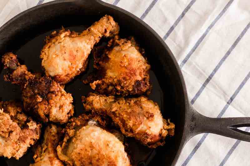 Buttermilk fried chicken in a cast iron skillet with crispy breading.