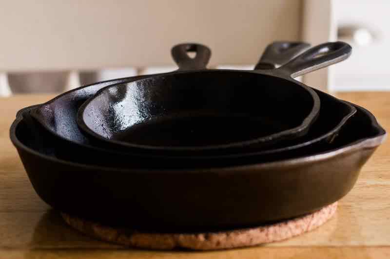 Three seasoned cast iron skillets stacked inside each other.