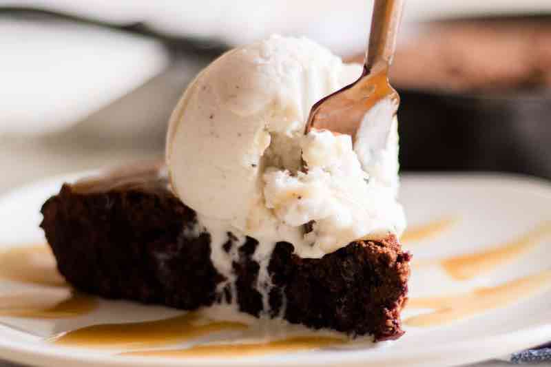 Slice of double chocolate skillet brownie with a scoop of ice cream on top.