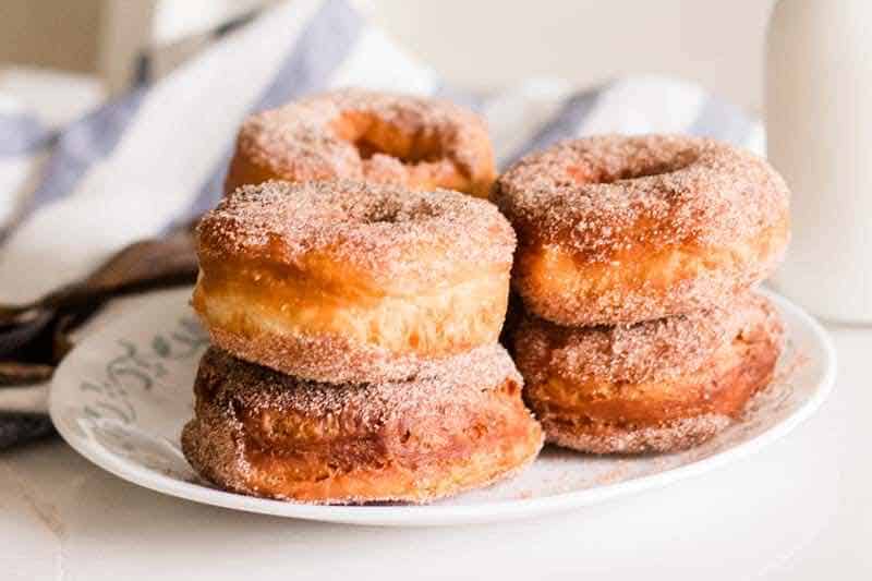 Homemade cinnamon sugar donuts on white plate.