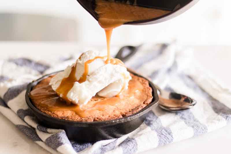 Pouring sauce on top of homemade skillet blondie.