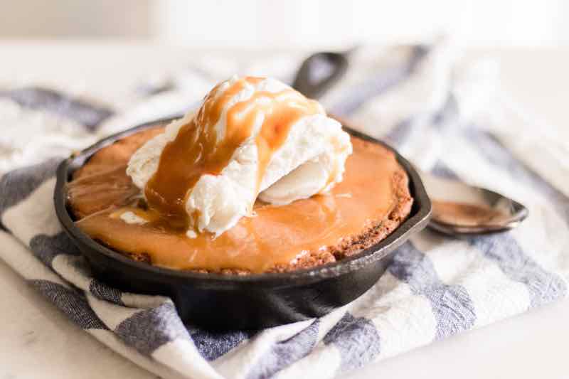 Homemade blondie topped with a scoop of ice cream and drizzled with maple butter vanilla sauce.