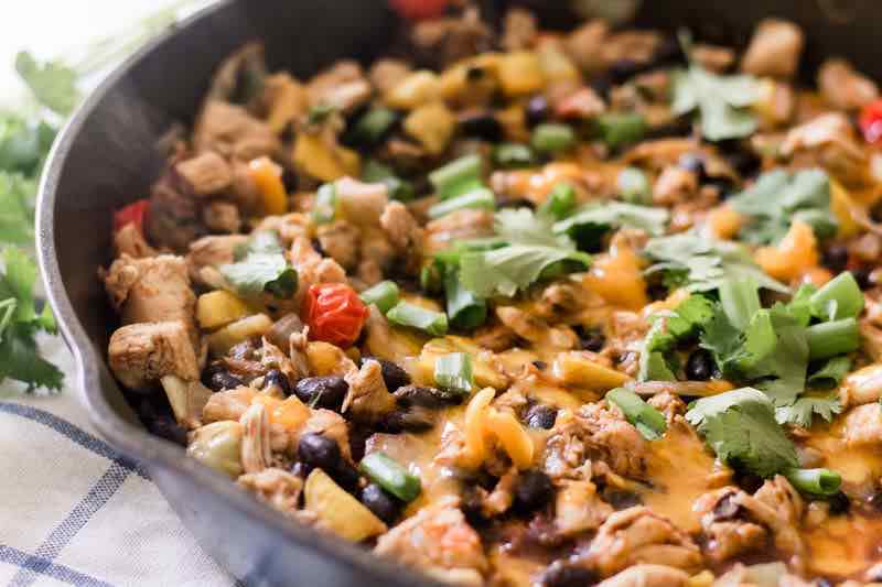 Mexican style cheese, chicken and bean casserole in a cast iron skillet. 