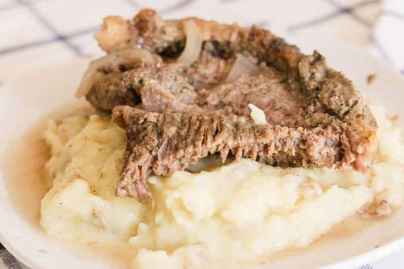 Slow Cooked Round steak atop a mountain of mashed potatoes.