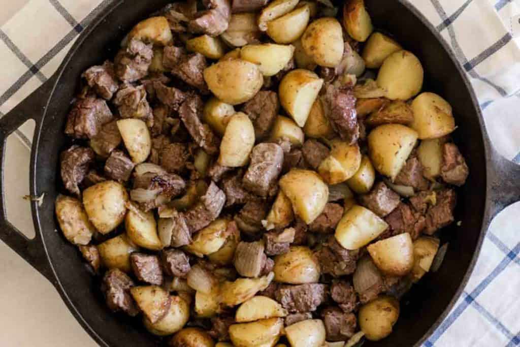 Steak and potato bites in a cast iron skillet.