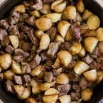 Steak and potato bites in a cast iron skillet.