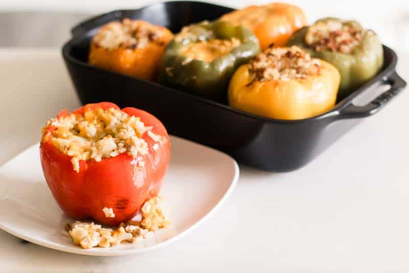 Stuffed sausage and cheese bell peppers on small white plate.
