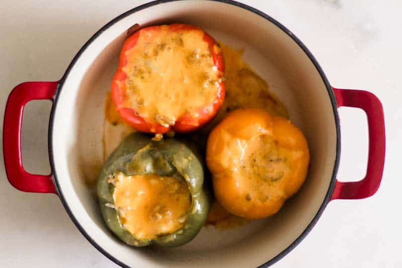 Dutch Oven stuffed peppers topped with cheddar cheese.