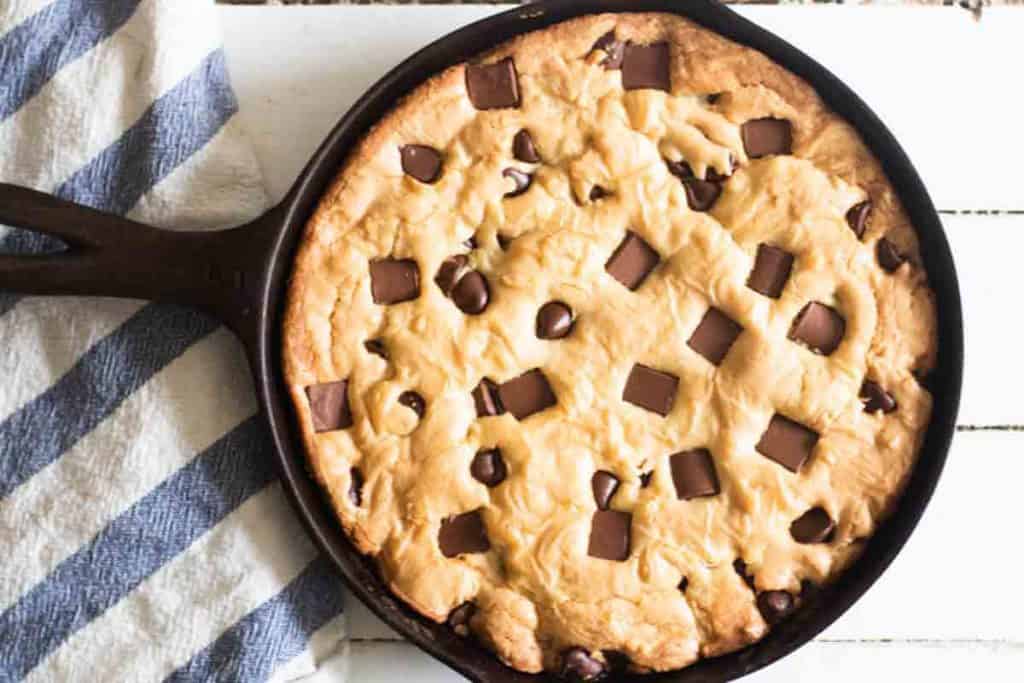 Deep dish chocolate chip cookie in a small cast iron skillet.