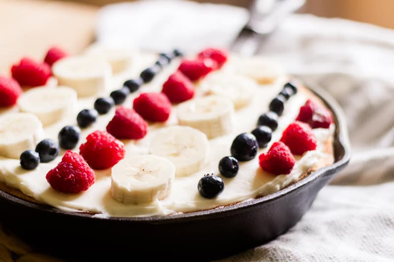 Red white and blue cake with raspberries blueberries and bananas.
