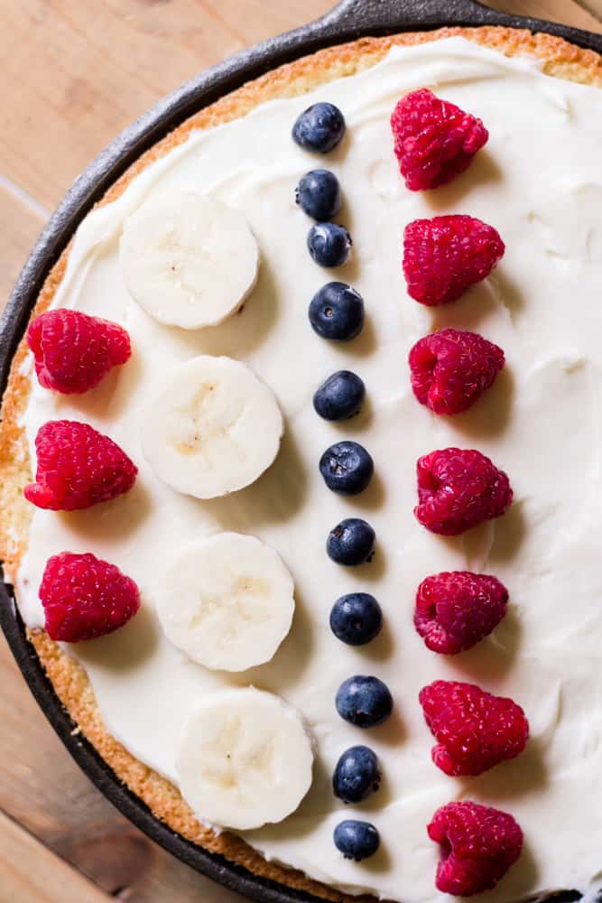 White sheet pan cake bake in a cast iron skillet with homemade cream cheese icing.