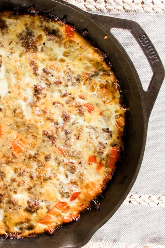 Cast iron breakfast casserole topped with white cheddar cheese.