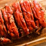 Tender tasty homestyle meatloaf cut on wooden tabletop.