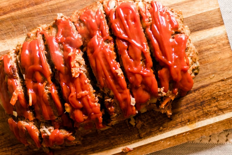 Tender tasty homestyle meatloaf cut on wooden tabletop.