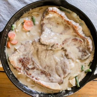 Creamy smothered pork chops in a cast iron skillet.