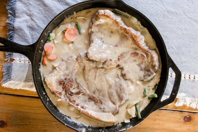 Creamy smothered pork chops in a cast iron skillet.