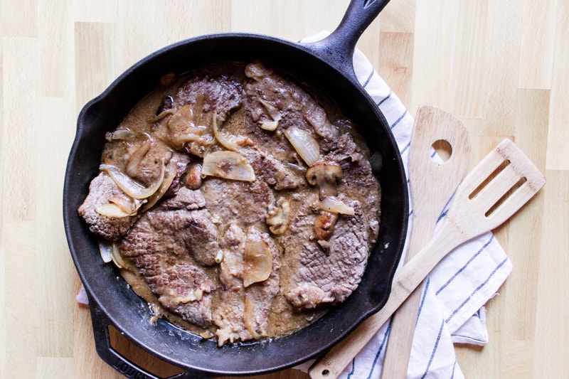 Skillet round steaks smothered in gravy with onions and mushrooms.