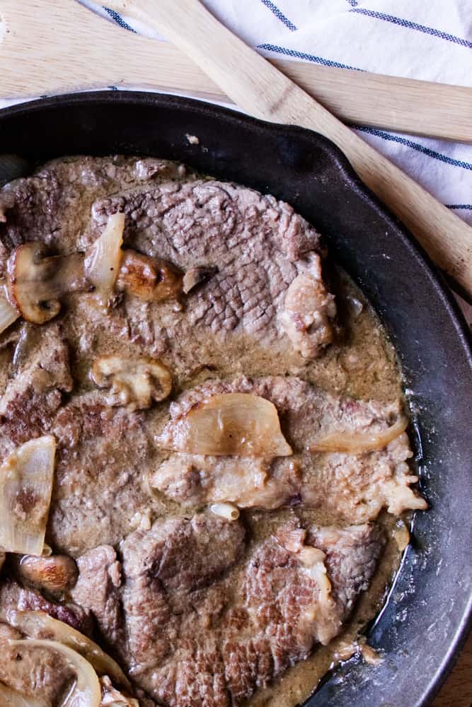 Seared and simmered round steak in a cast iron skillet. 