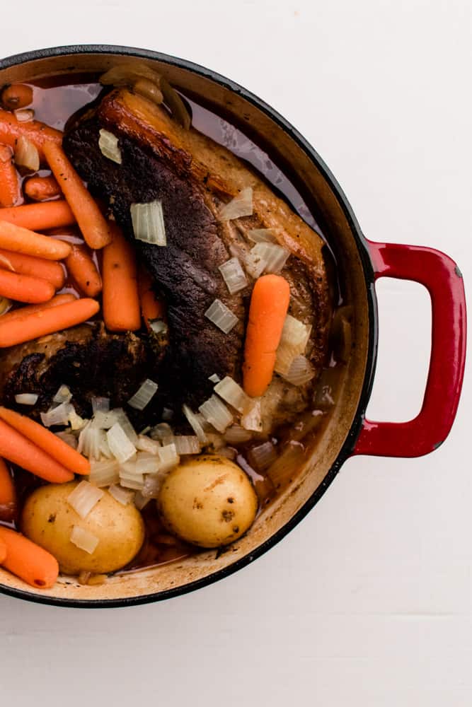 Oven braised brisket with carrots potatoes and onions.