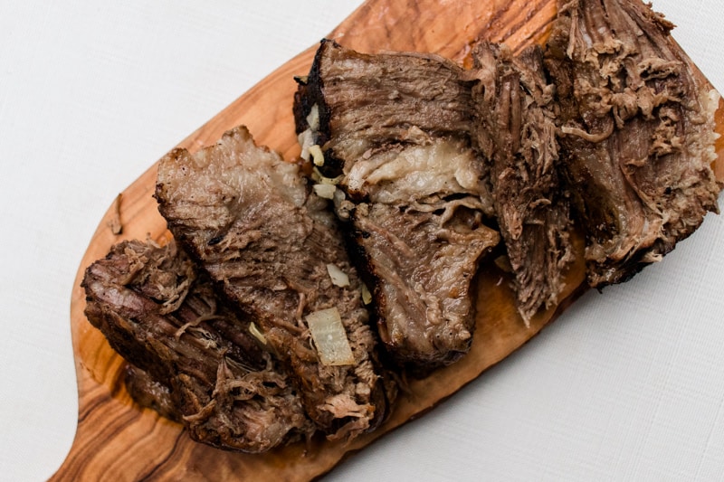 Sliced brisket on wooden cutting board.