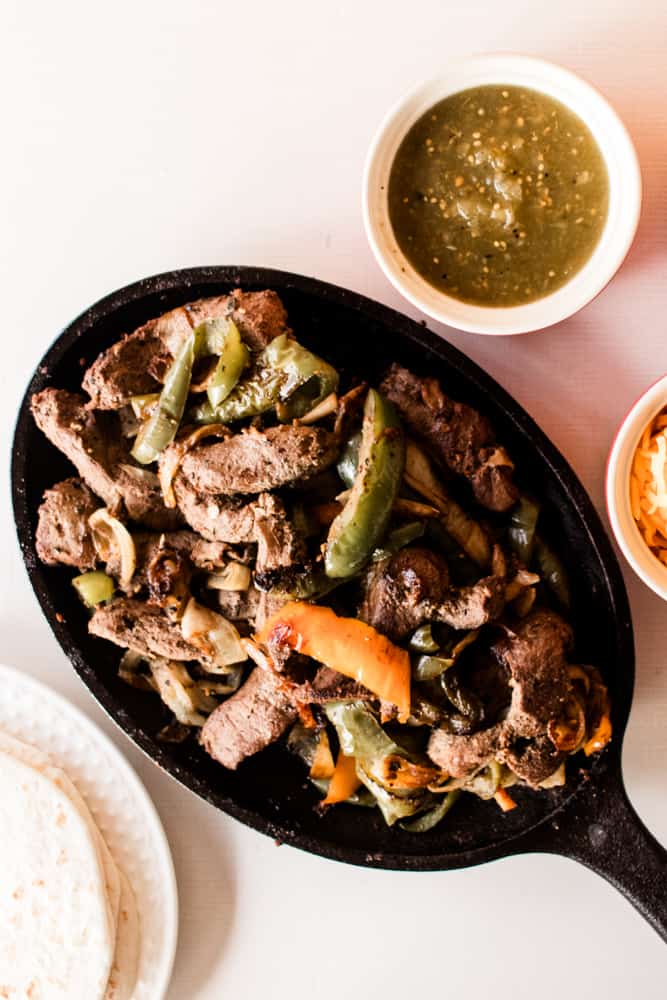 Homemade restaurant fajitas with peppers and onions in a fajita skillet.