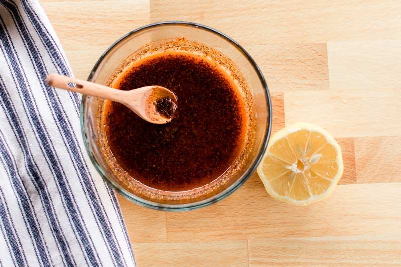 Homemade cajun chicken rub stirred into melted butter on a wooden countertop.