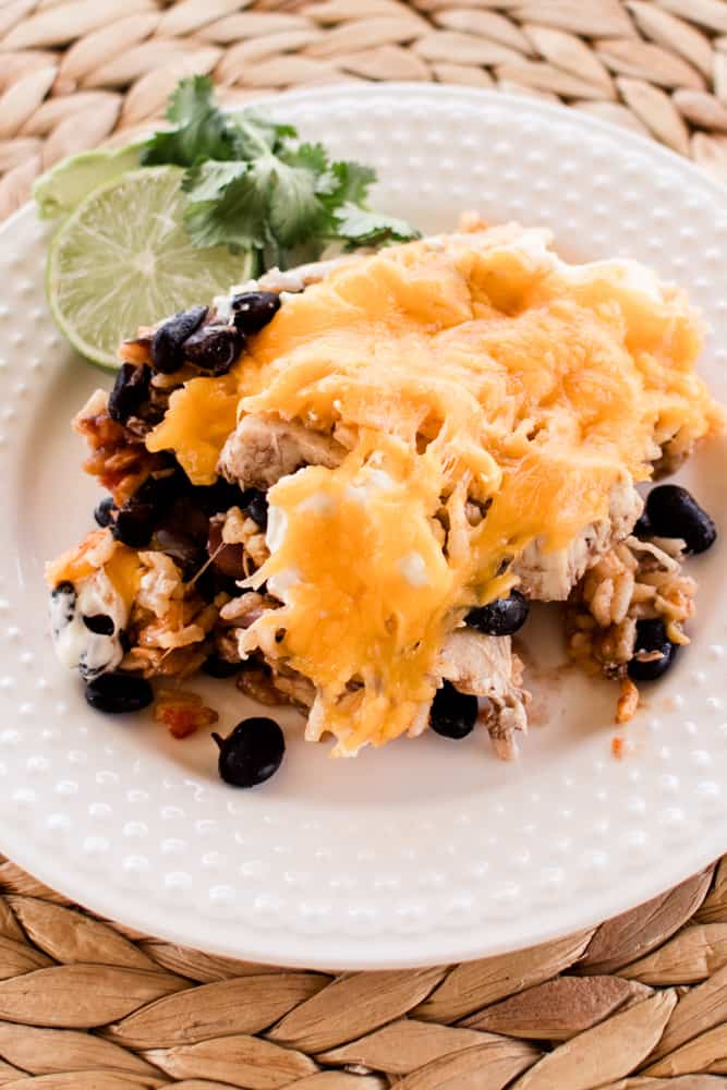 White plate with hot southwest chicken casserole filled with beans, rice, chicken and cheese.