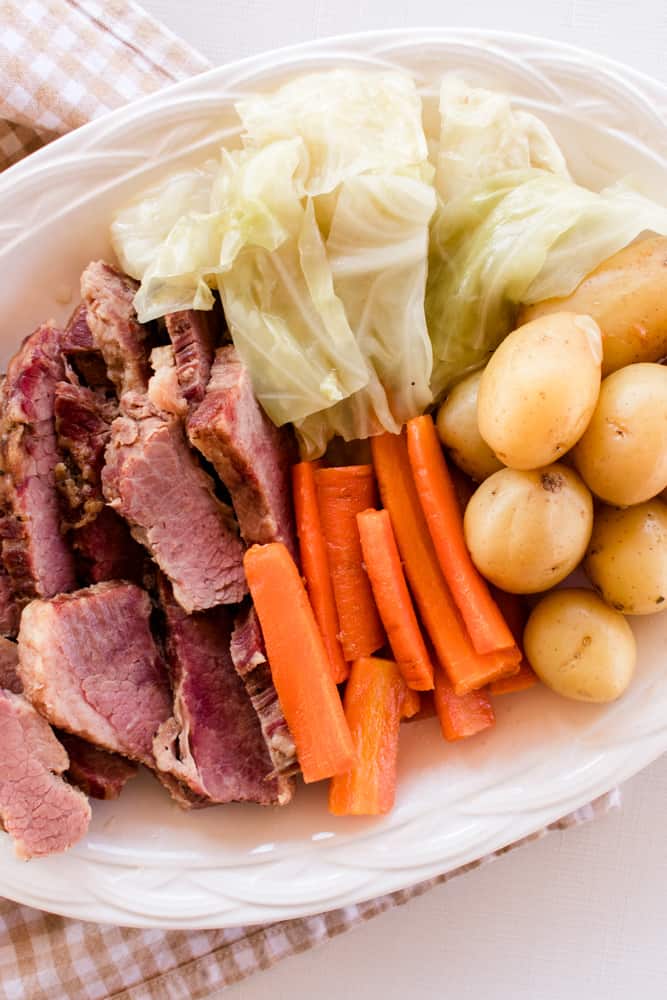 Platter of dutch oven made corned beef brisket with cabbage, carrots and baby potatoes.