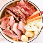 Corned beef with baby potatoes, carrots, onions, cabbage and onions in a dutch oven.