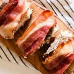 Bacon wrapped deer tenderloin on a cooking towel and a marble kitchen counter.