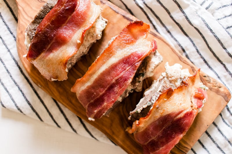 Bacon wrapped deer tenderloin on a cooking towel and a marble kitchen counter.