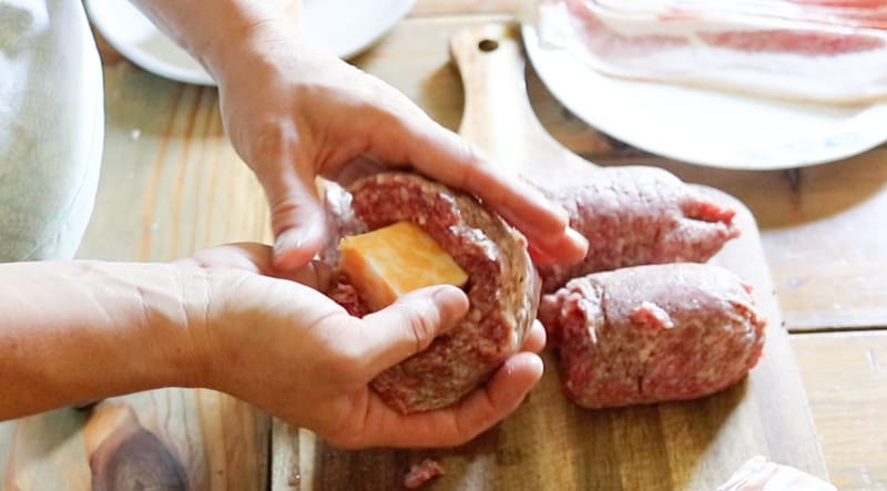 Stuffing raw burger meat with cheese.