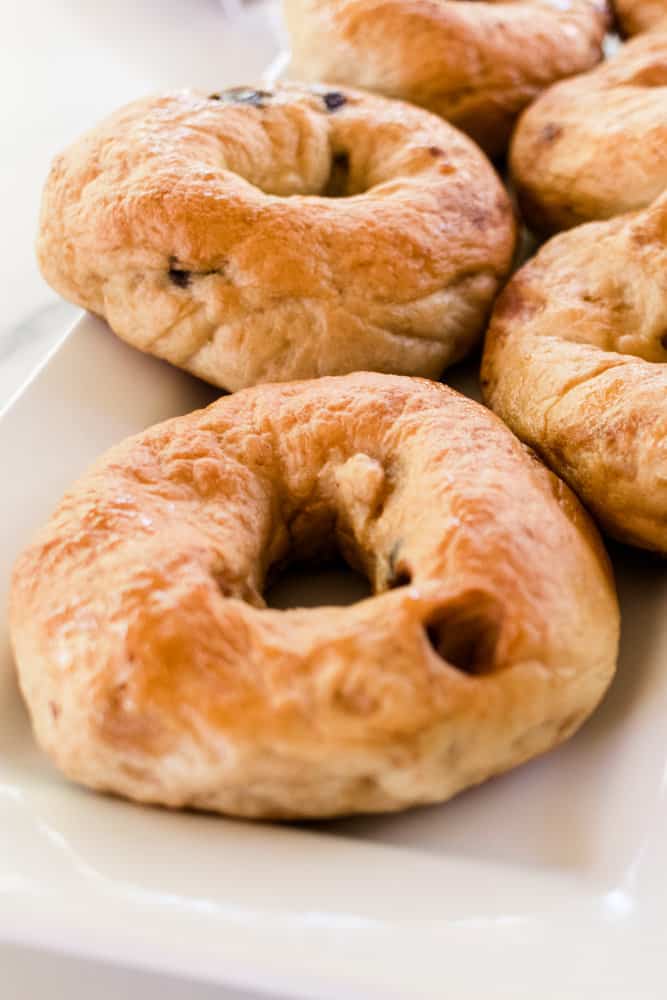 Homemade vegan chocolate chip bagels on a white serving tray.