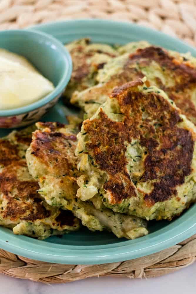 Homemade zucchini cakes cooling on a plate.