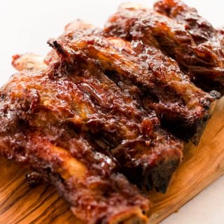 Oven baked beef back ribs on a wooden cutting board.