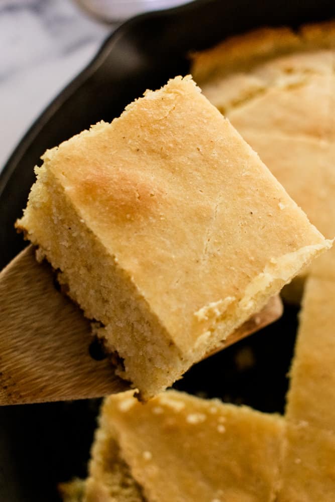 Scooping the cornbread out of the skillet.
