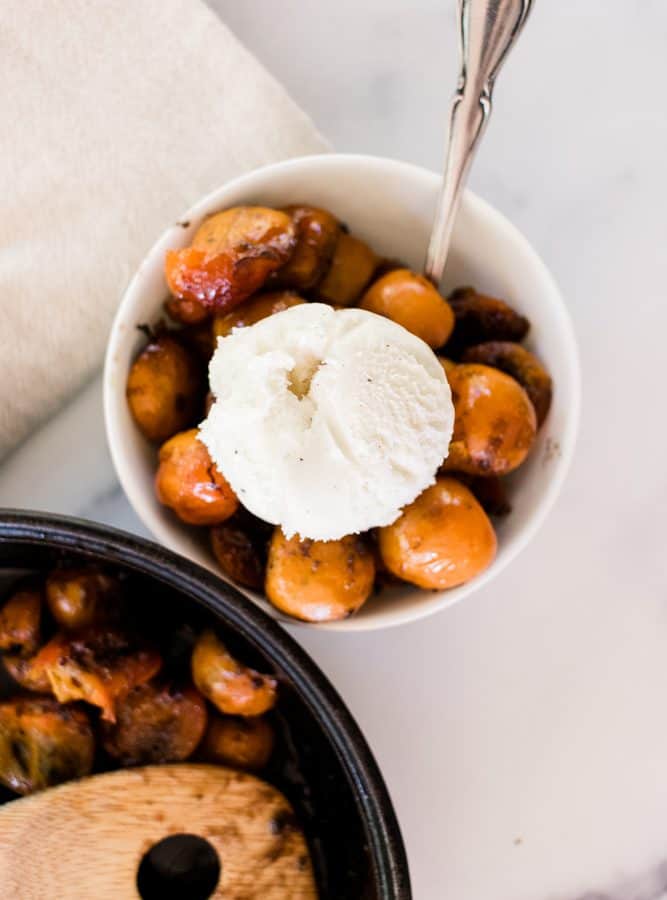 Baked persimmons in a small bowl with ice cream.