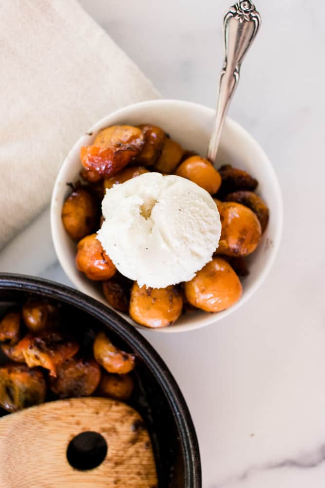 Bowl of cast iron spiced baked persimmons topped with vanilla ice cream. 