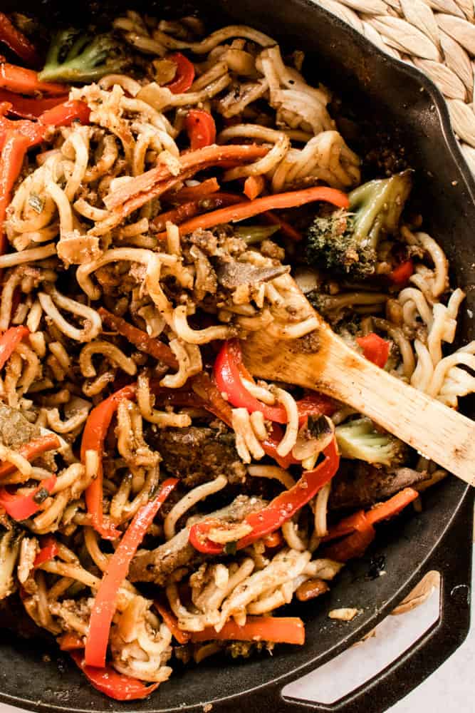A beef liver recipe with noodles and vegetables in a large cast iron skillet.