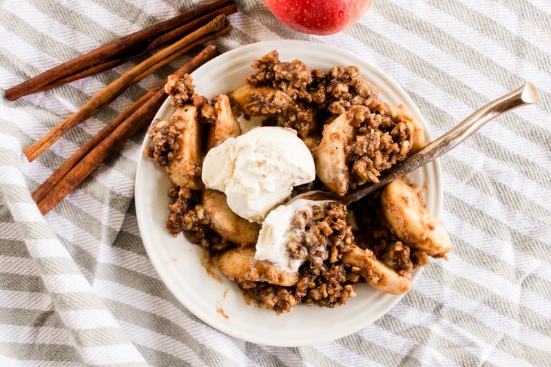 Dutch oven apple crisp with pecans topped with vanilla ice cream.