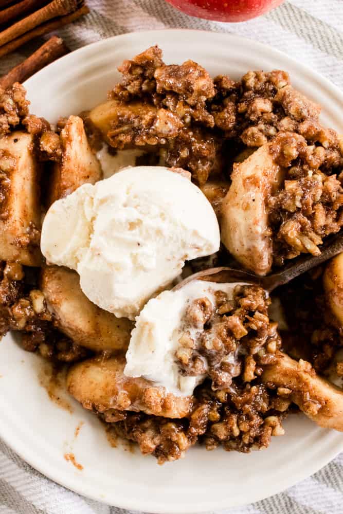 Homemade apple crips on a white plate with a scoop of ice cream.