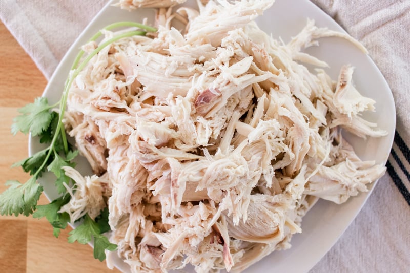 Tender shredded chicken with a sprig of parsley on a white place, ready for your favorite recipe.