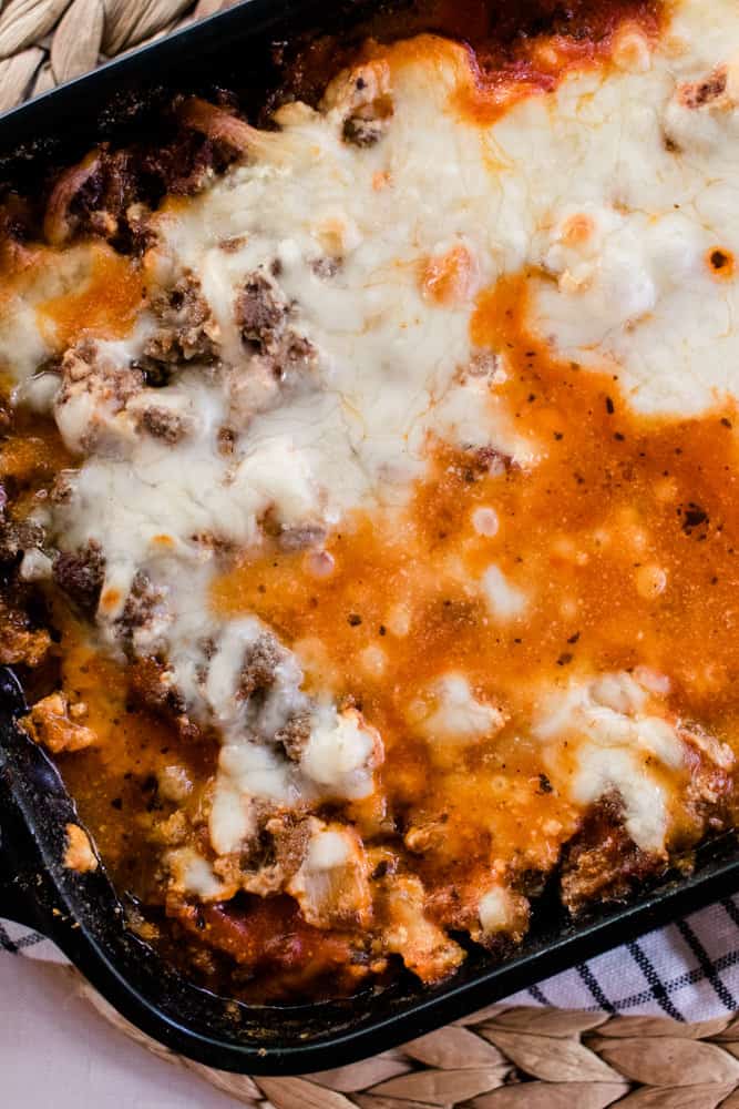 Zucchini lasagna with melted cheese and browned beef and sausage on a wicker mat.