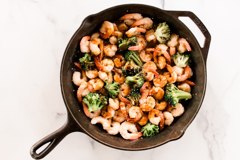 Cast iron skillet filled with honey garlic butter shrimp and broccoli. 