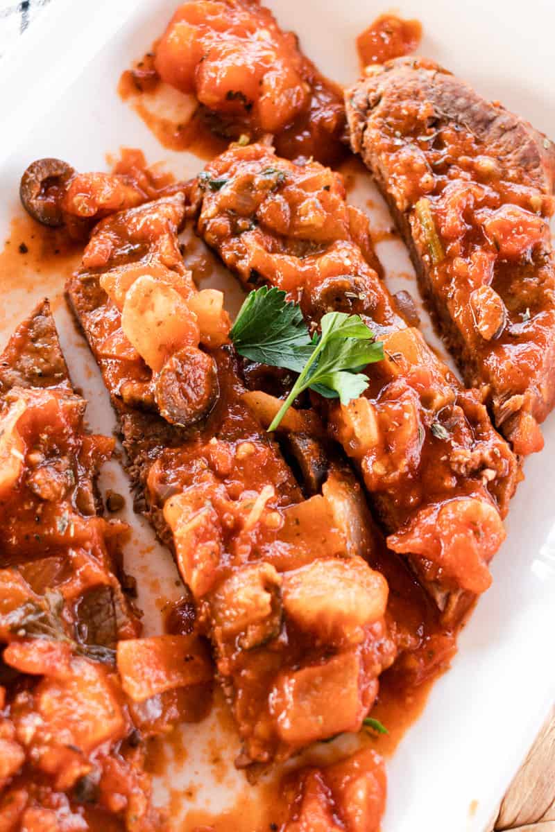 Sliced Steak Pizzaiola with fresh herbs.