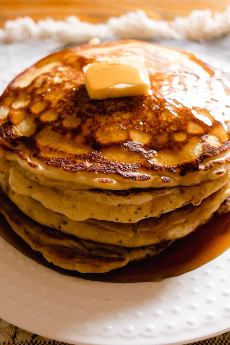 Tall stack of cast iron pancakes with butter melting off the top.