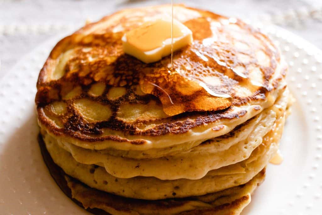 Drizzling fluffy pancakes with maple syrup.