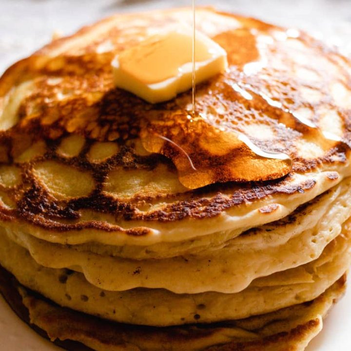 Drizzling fluffy pancakes with maple syrup.
