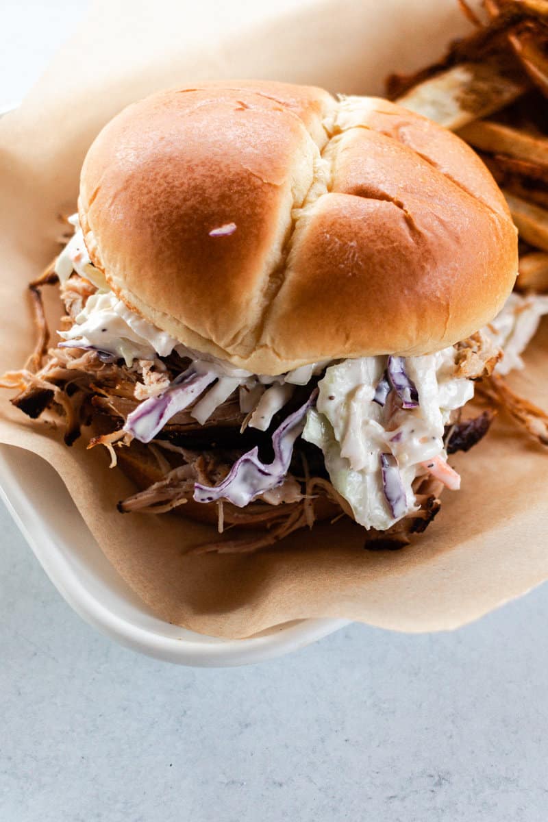 Dutch oven pulled pork on a bun, served with slaw and fries.