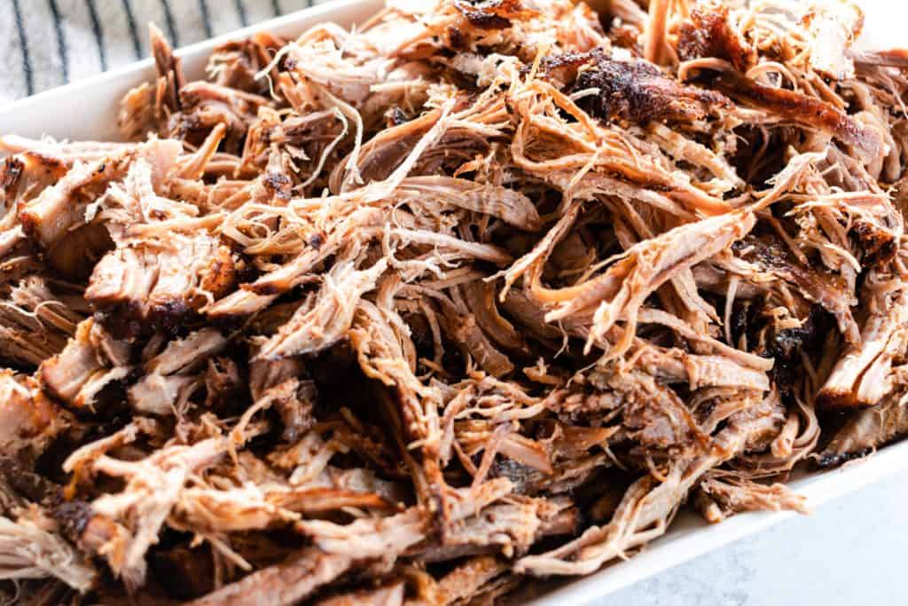 Dutch oven pulled pork on a white serving tray.